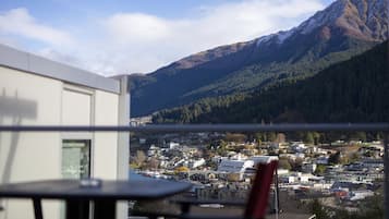 A balcony with a table and chairs overlooking a town and mountains.