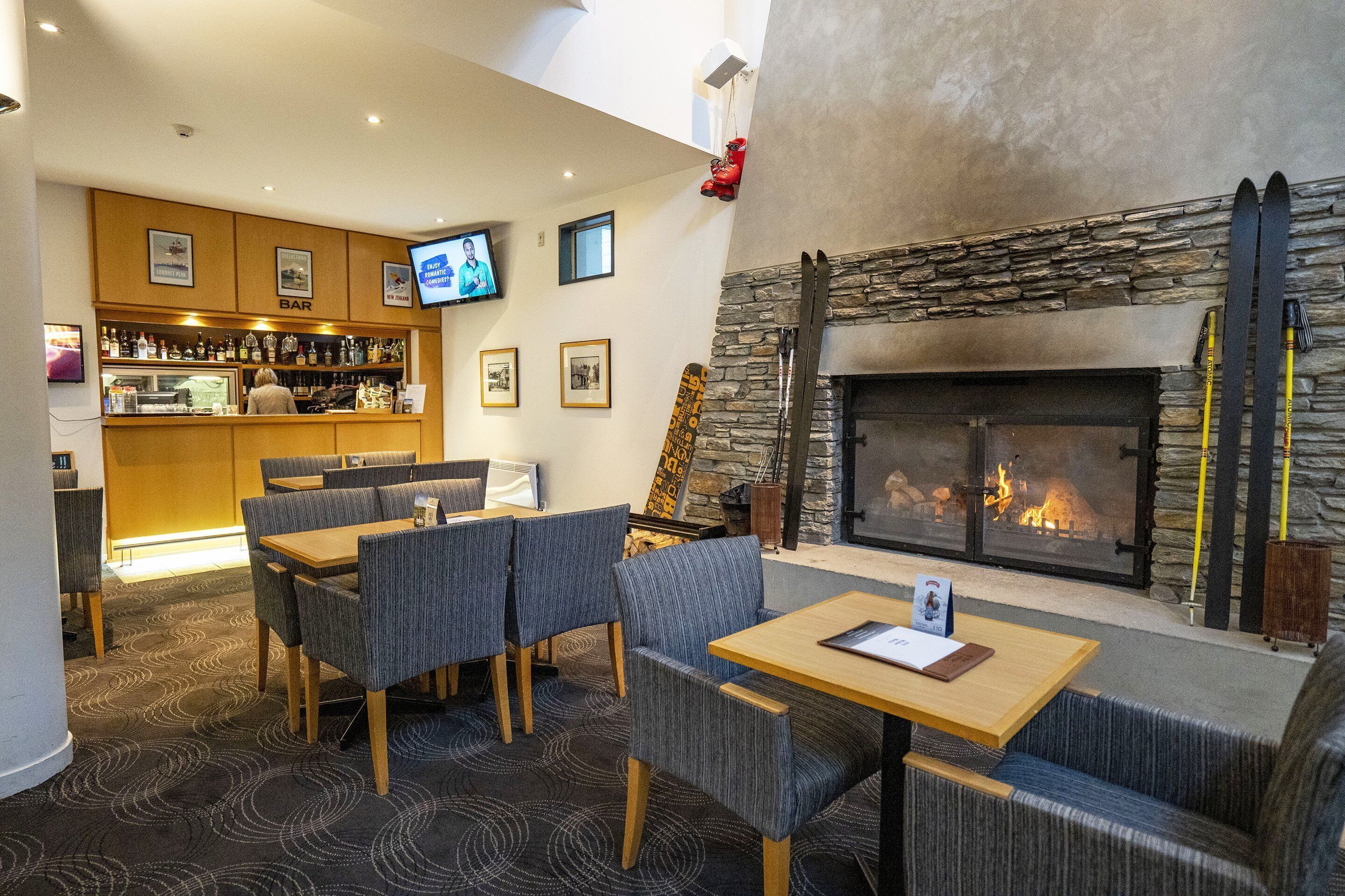 A bar area with a television, a fireplace with a stone surround, and seating arrangements.