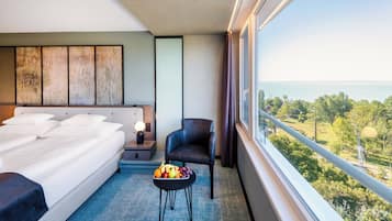 Ein Hotelzimmer mit Bett, einem Sessel, einem kleinen Tisch mit Früchten und Meerblick.