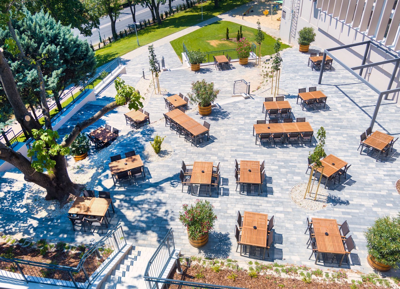 An outdoor seating area with multiple tables and chairs, surrounded by potted plants and trees.