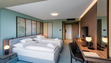 A hotel room with a large bed, a desk with a computer, a chair, and a mirror.