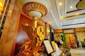 A lobby with a golden statue, a reception desk, and a chandelier. - Tianci Service Apartment (Shanghai)