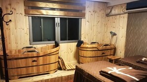 Een houten kamer met een bed, twee houten badkuipen, een raam en een lamp.