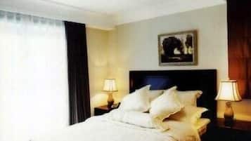Habitación de hotel con cama, dos lámparas de noche, un cuadro en la pared y ventana con cortinas.