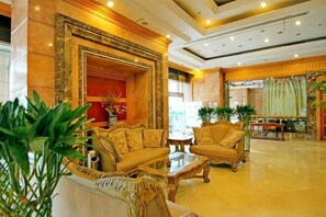 A lobby with a reception desk, seating area with sofas and armchairs, and a large decorative mirror. - Tianci Service Apartment (Shanghai)