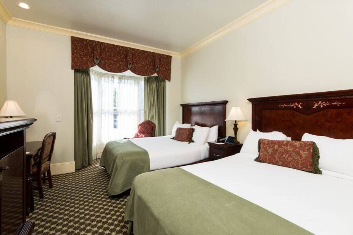 A hotel room with two beds, a desk, and a chair.