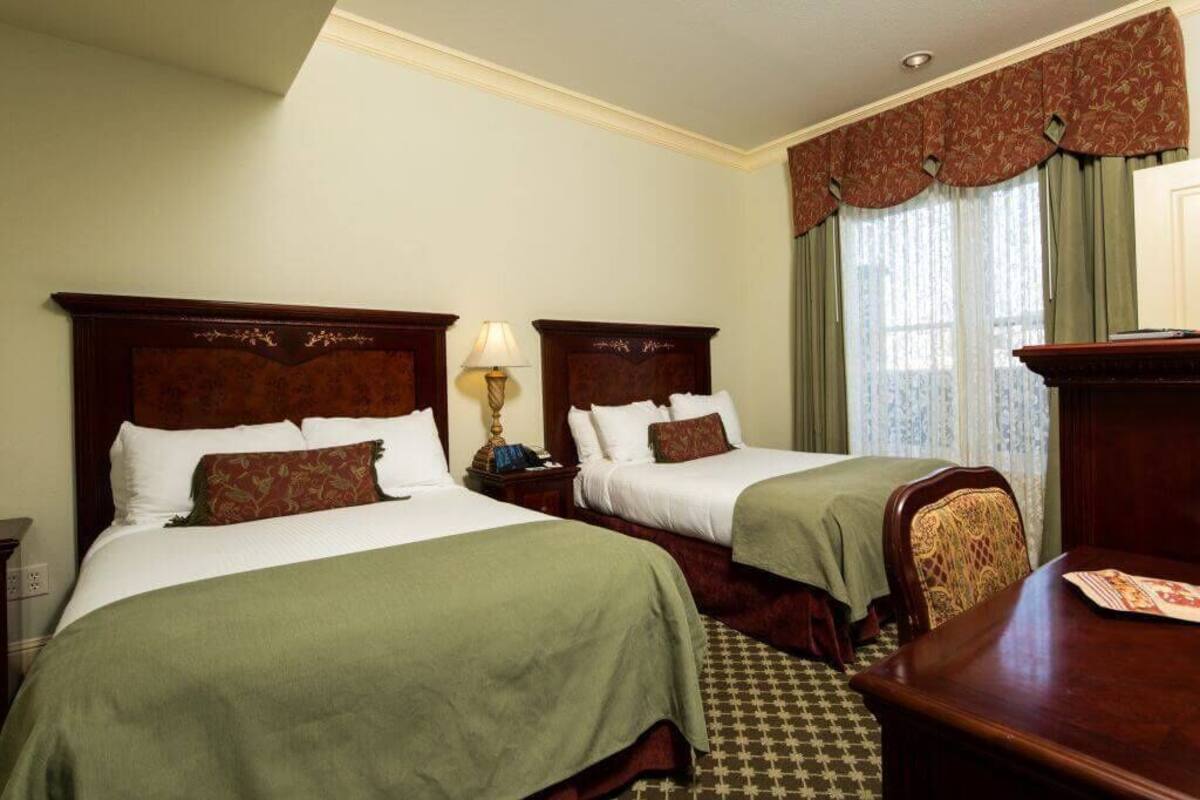 A hotel room with two single beds, a desk, and a chair.