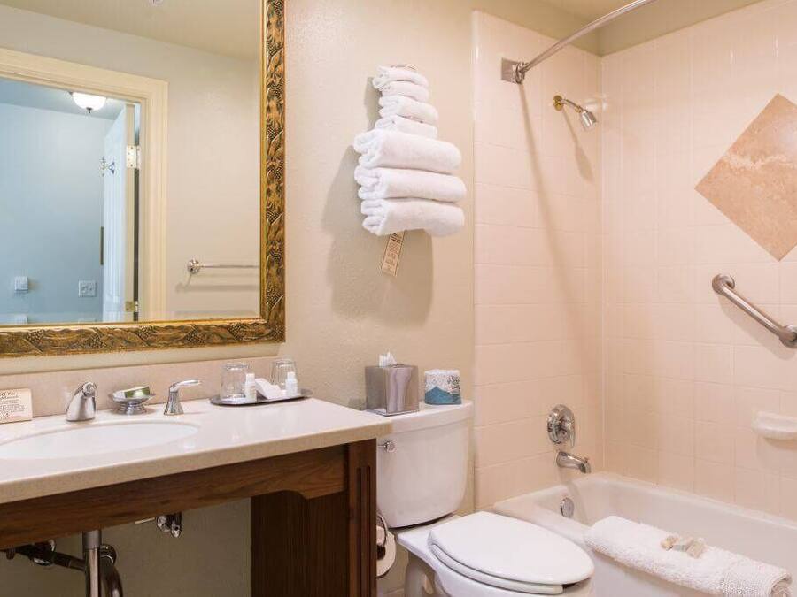 A bathroom with a sink, toilet, and bathtub. There are towels hanging on the wall and a showerhead.