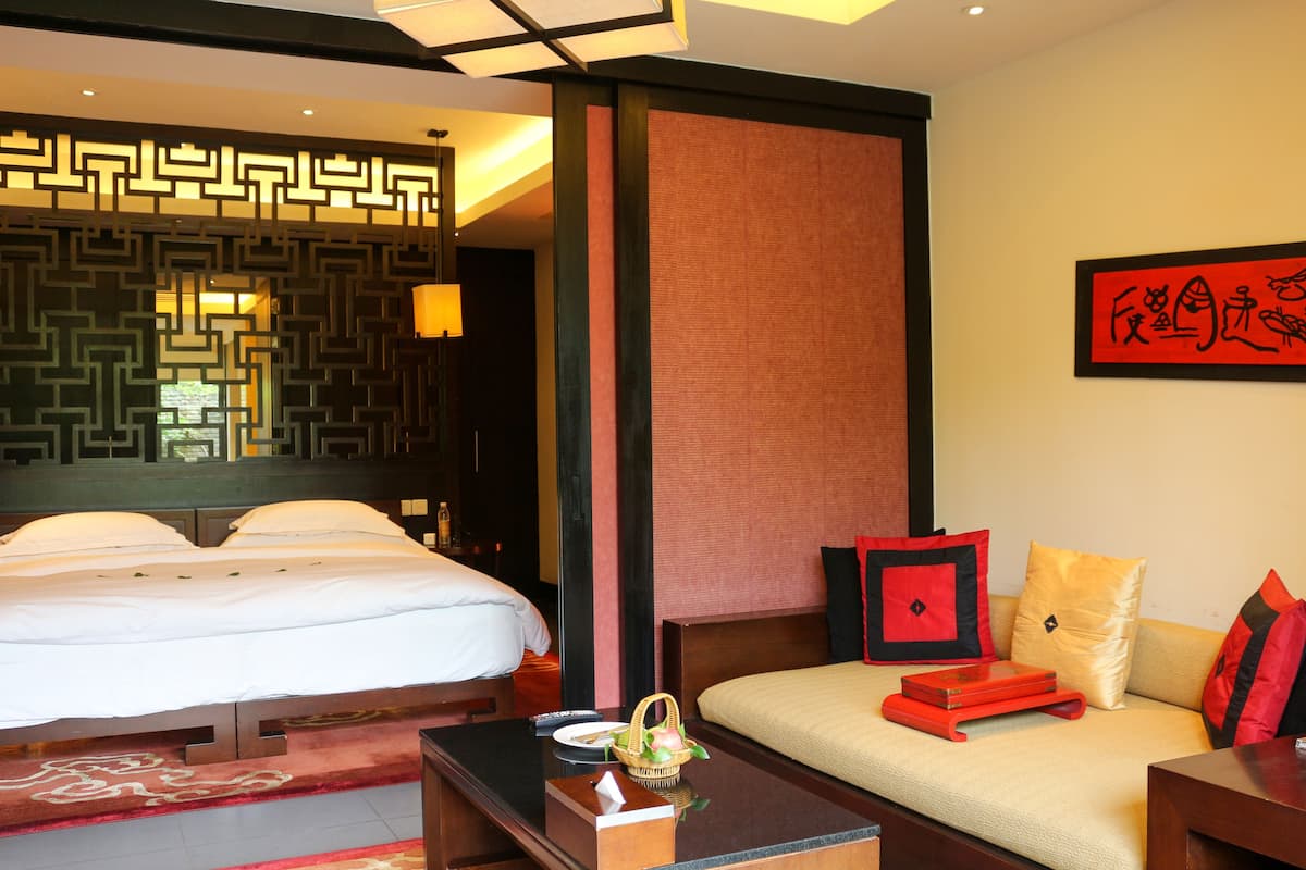Una habitación de hotel con cama, sofá, una mesita y un panel decorativo en la pared.