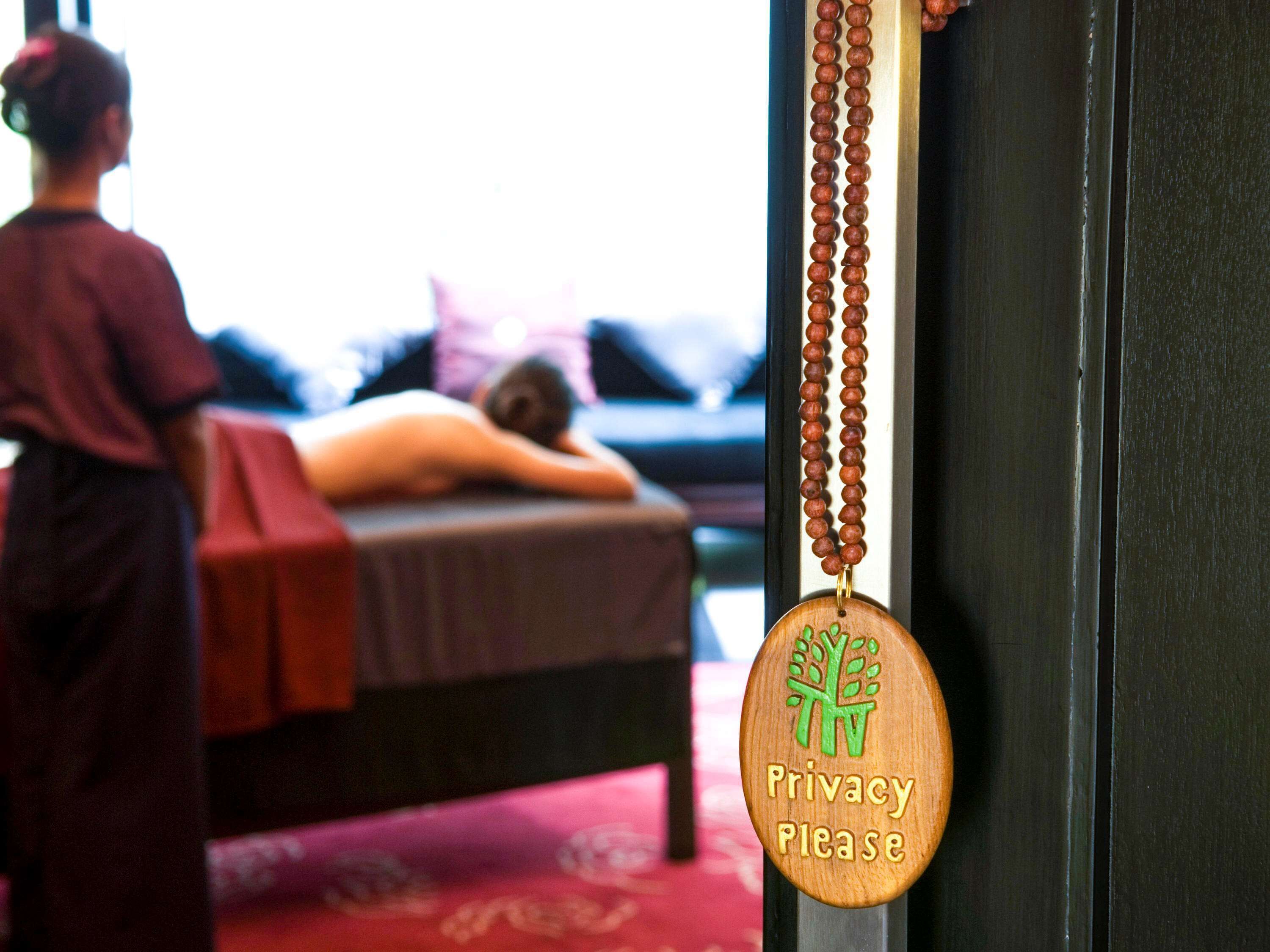 A massage room with a privacy sign, a wooden door, and a red carpet.