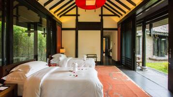 Relax in a traditional room with a large bed, greenery views, and a cozy reading area.