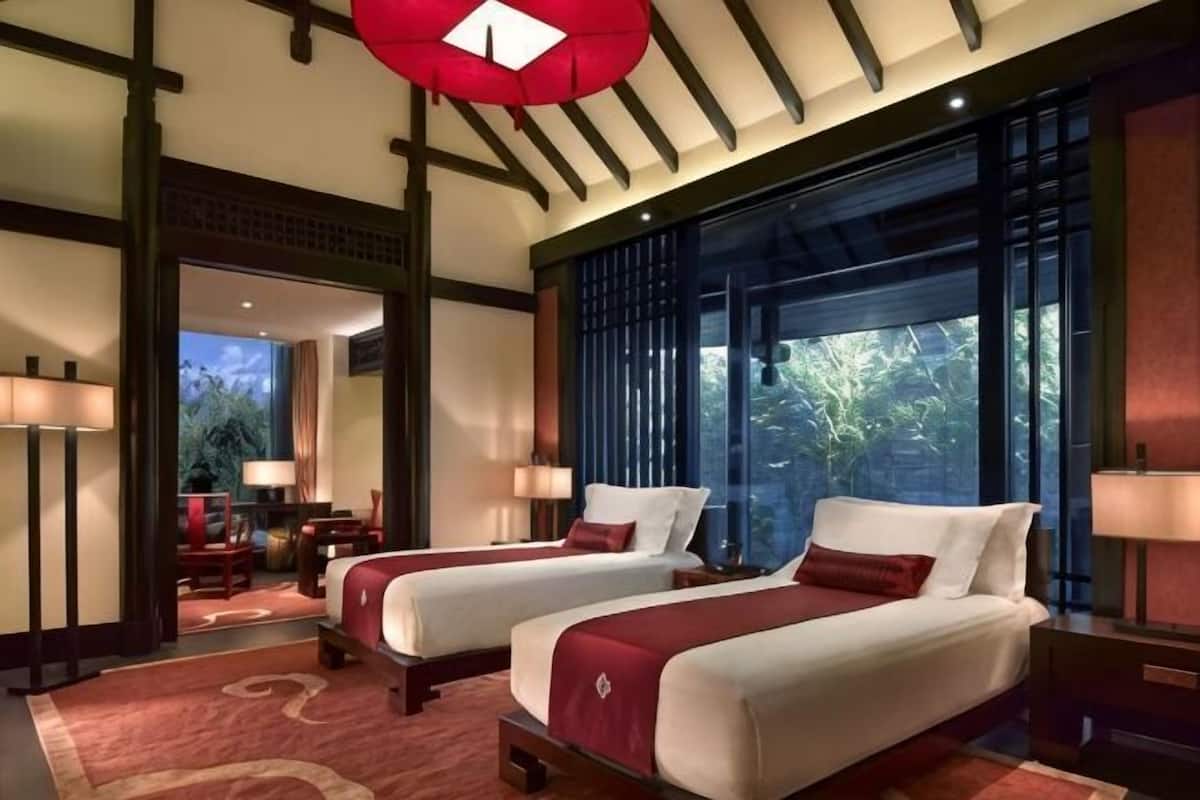 Habitación de hotel con dos camas, un ventanal grande y vistas al exterior.