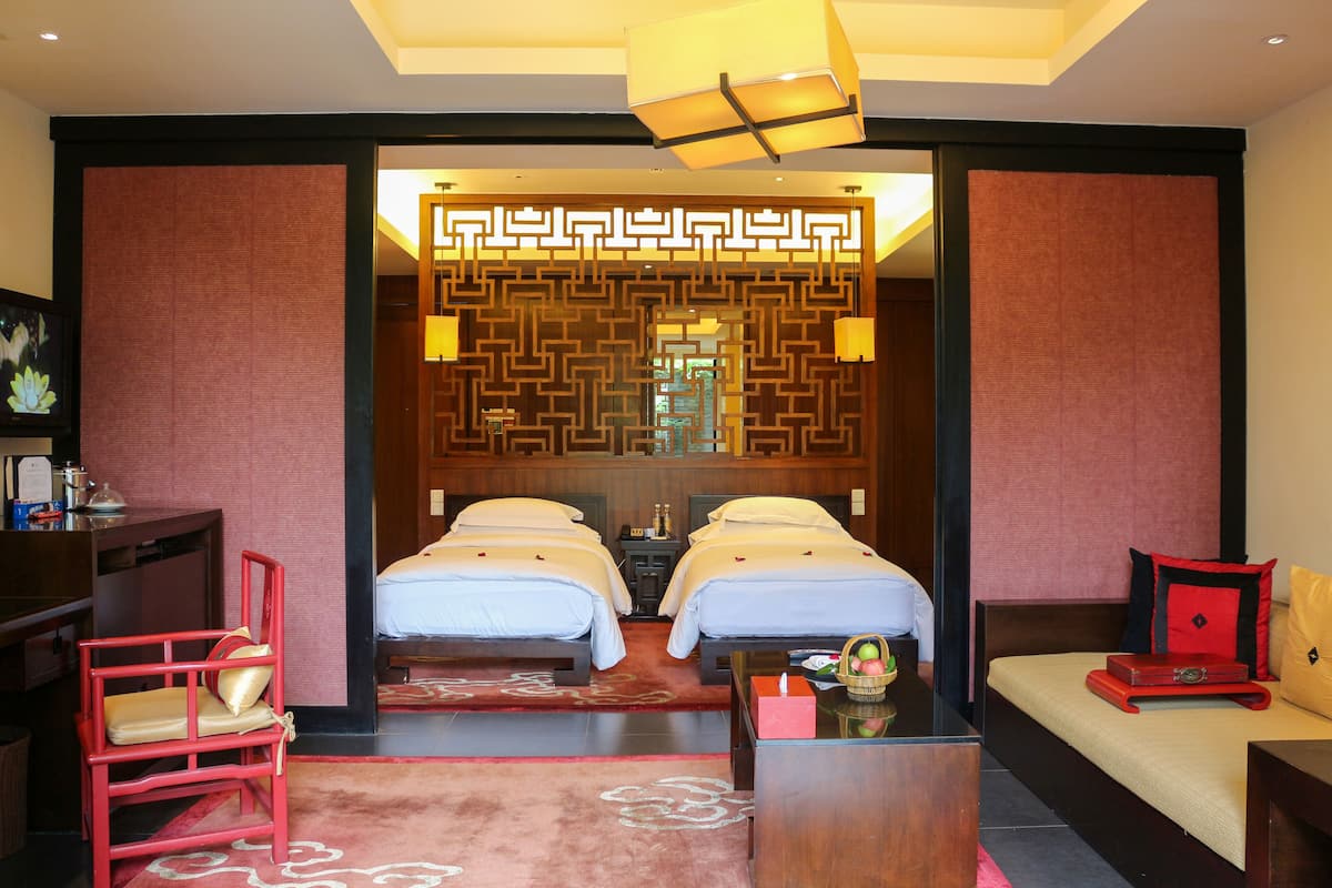 Habitación de hotel con dos camas, un sofá, un escritorio y un biombo decorativo.