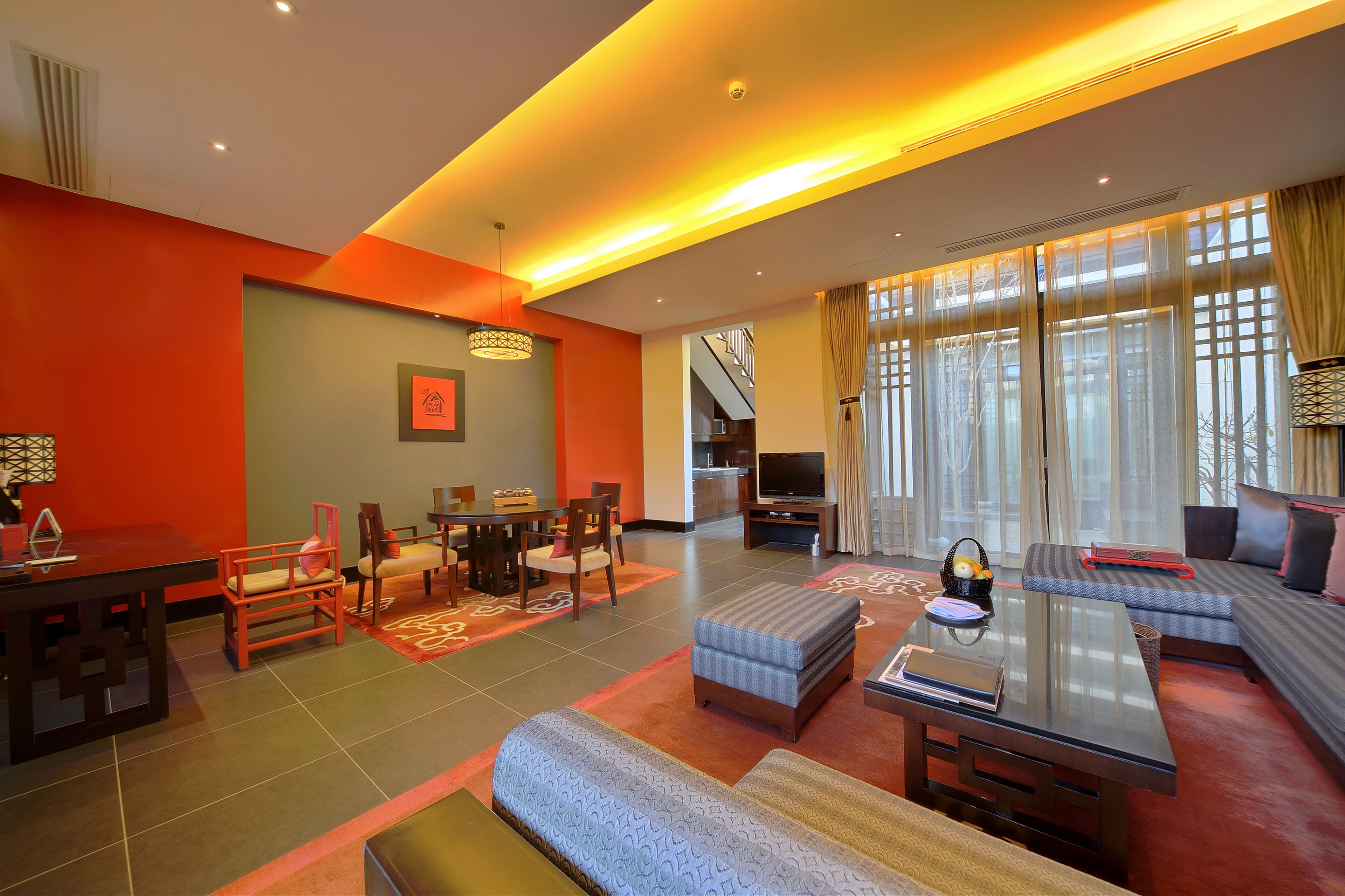 Una sala de estar moderna con un sofá, un reposapiés, una mesa de centro y un comedor con sillas y una mesa.