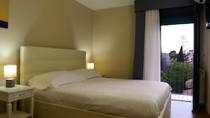 A hotel room with a bed, bedside table, and a view through a window. - Hotel Centrum (Catania)