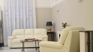 A living room with a cream-colored sofa, a small wooden coffee table, a lamp, and a vase with flowers. - Hotel Centrum (Catania)