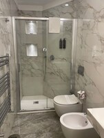 Un baño moderno con ducha de vidrio, inodoro y bidé.