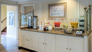 A kitchen with a granite countertop, white cabinets, a coffee maker, a blender, and a framed picture of a building. - Five Towns Inn - JFK Airport (Lawrence)
