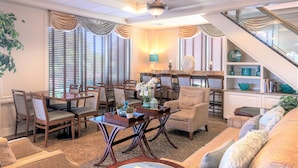 A spacious living room with a dining area, a staircase, and a view of the outdoors. - Five Towns Inn - JFK Airport (Lawrence)