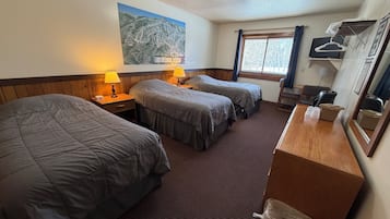 Habitación de hotel con dos camas, un escritorio de madera, un espejo, una ventana con cortinas y un mapa en la pared.