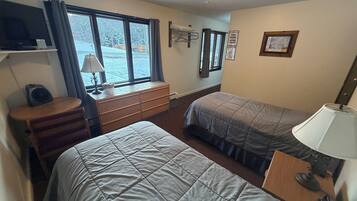 A hotel room with two beds, a desk, a chair, a TV, and a window with curtains.