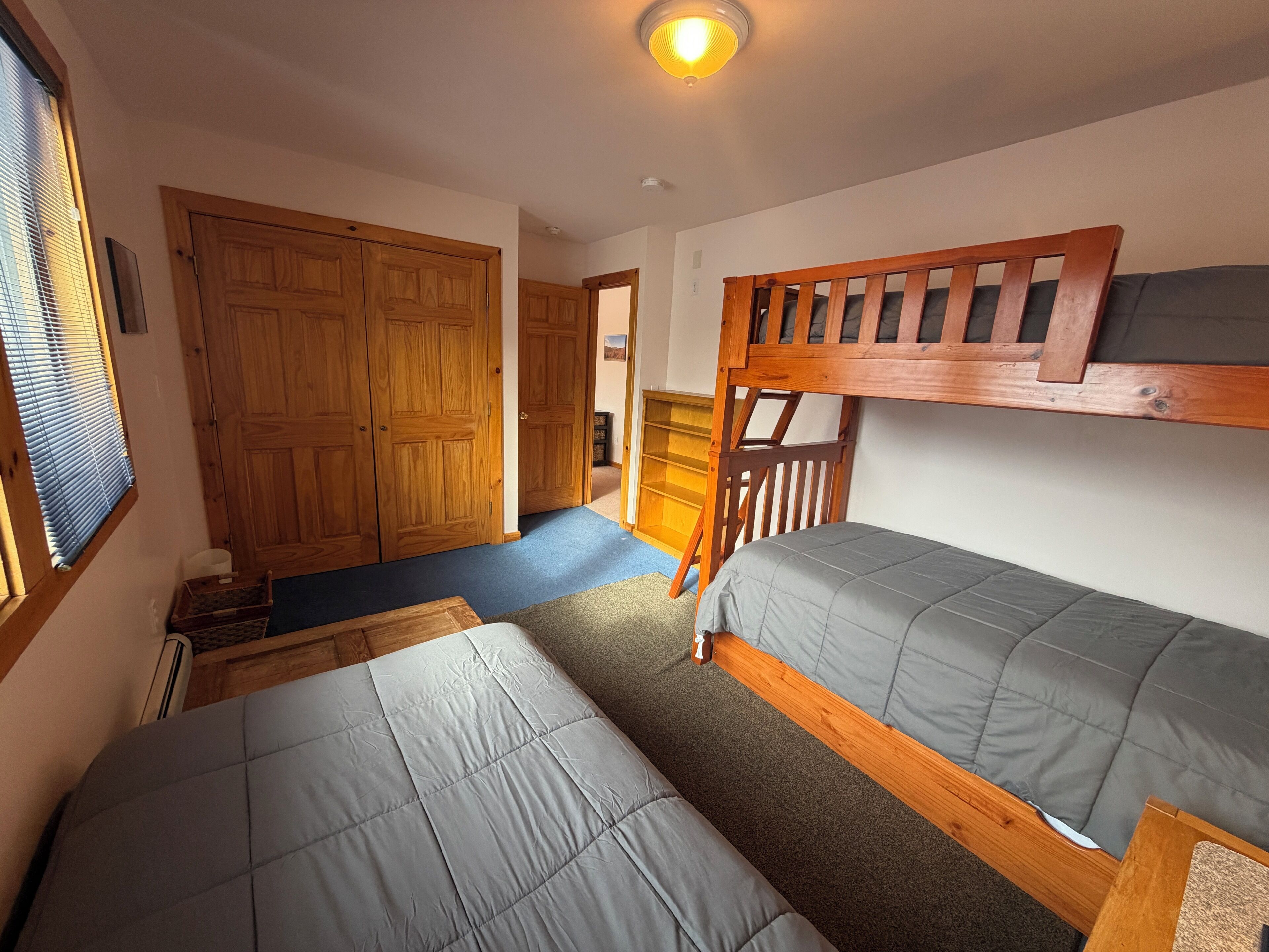 A room with two bunk beds, wooden wardrobe, and a small desk.