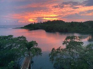 A calm river with a wooden bridge in the foreground and a forested island in the background. - Casa Caletas (Bejuco)