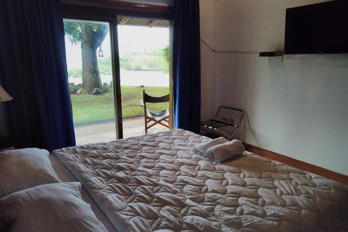 Un dormitorio con una cama grande, una silla y un televisor montado en la pared.