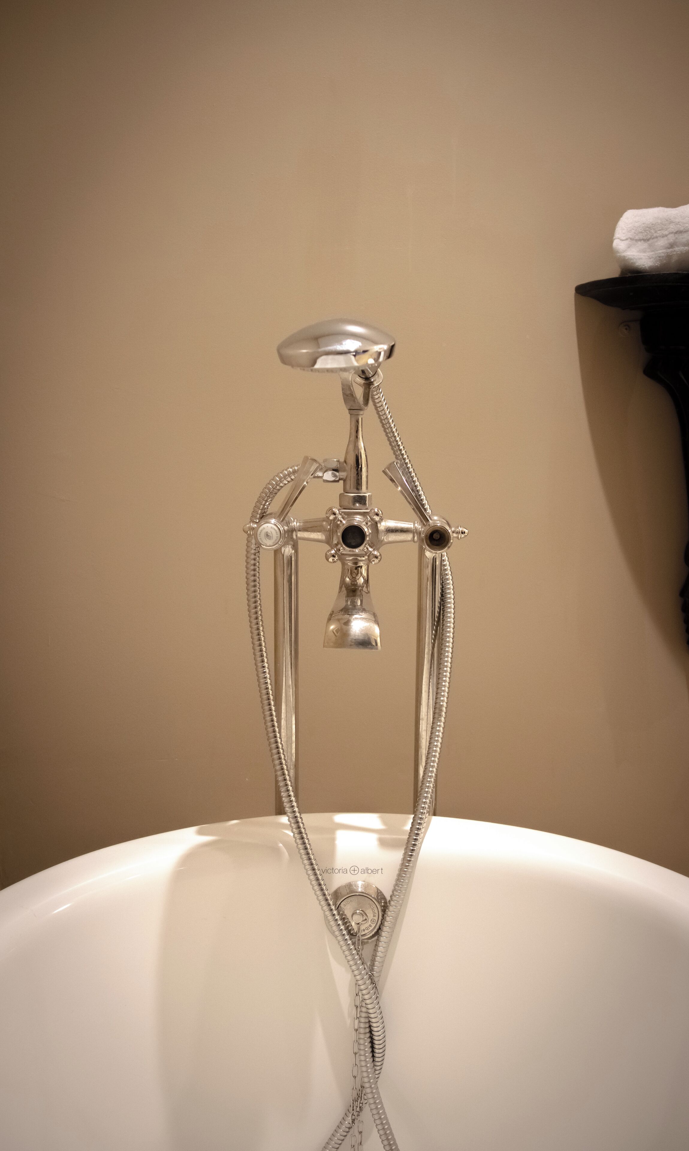 A bathroom with a bathtub, a shower head, and a towel rack.