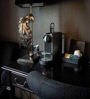 Un escritorio con una máquina de café, una lámpara decorativa y una taza de café.