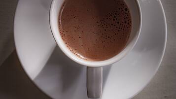 Une tasse de café posée sur une soucoupe, avec une cuillère et une fourchette sur une serviette.