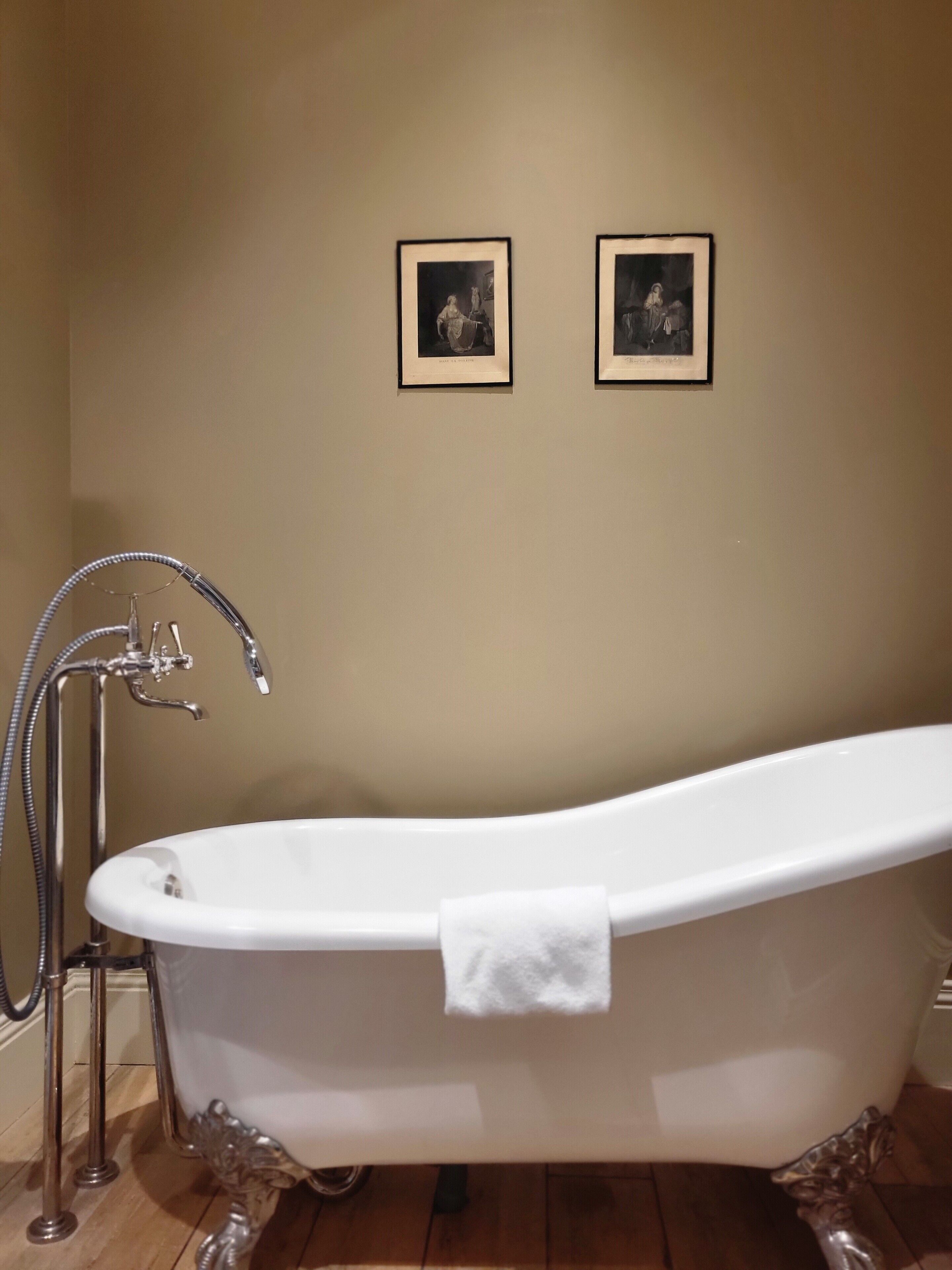 A white freestanding bathtub with a towel, a chrome faucet, and a showerhead.