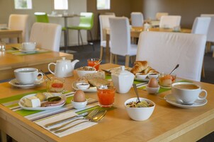 Mesa posta para o café da manhã, com diversos alimentos e bebidas.
