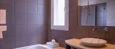 A modern bathroom with a bathtub, a sink, and a large mirror.