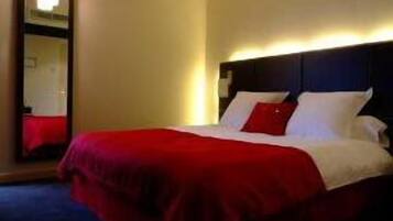 Een hotelkamer met een bed, nachtkastje en spiegel.