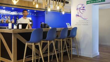 A bar area with a bartender, blue seating, and a sign indicating the suite location.