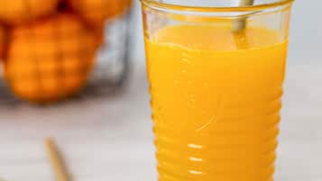A glass of orange juice with a straw in it.