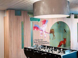 Una habitación con mesa de fútbol, paredes de madera y un mural con animales y texto.
