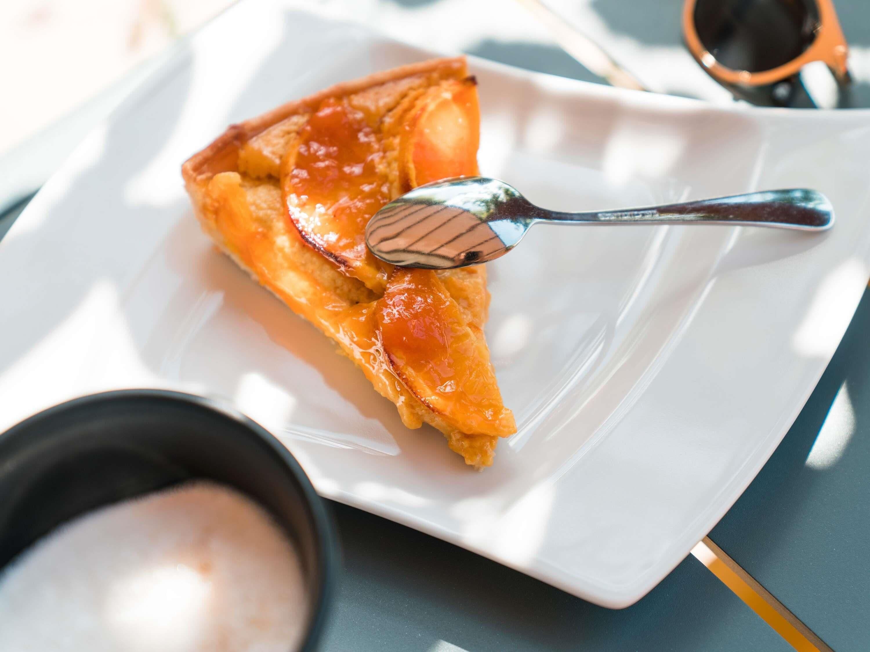 Une part de pizza sur une assiette blanche, avec une cuillère à côté.
