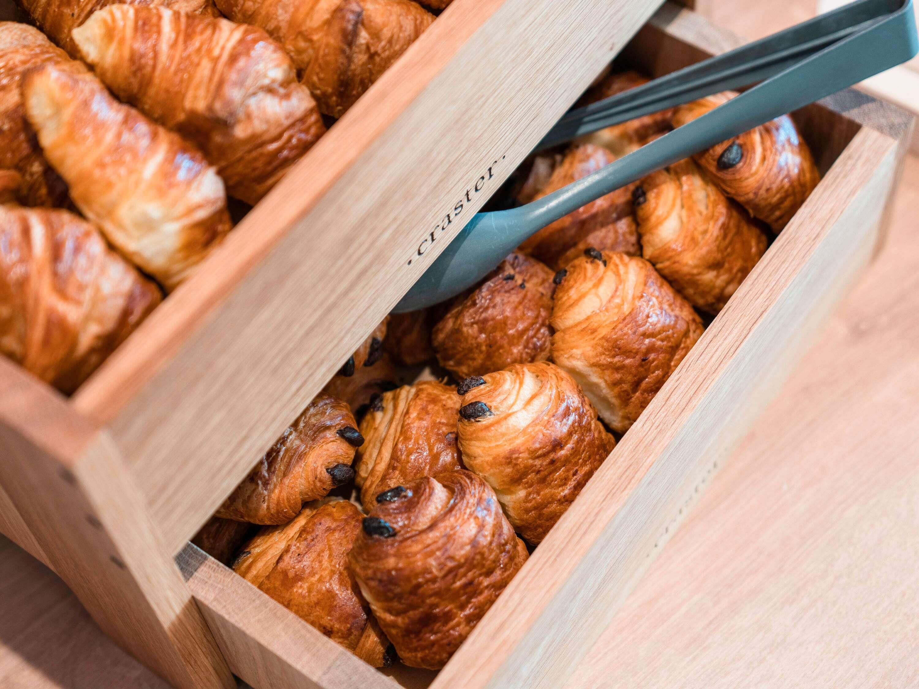 A wooden box filled with croissants.