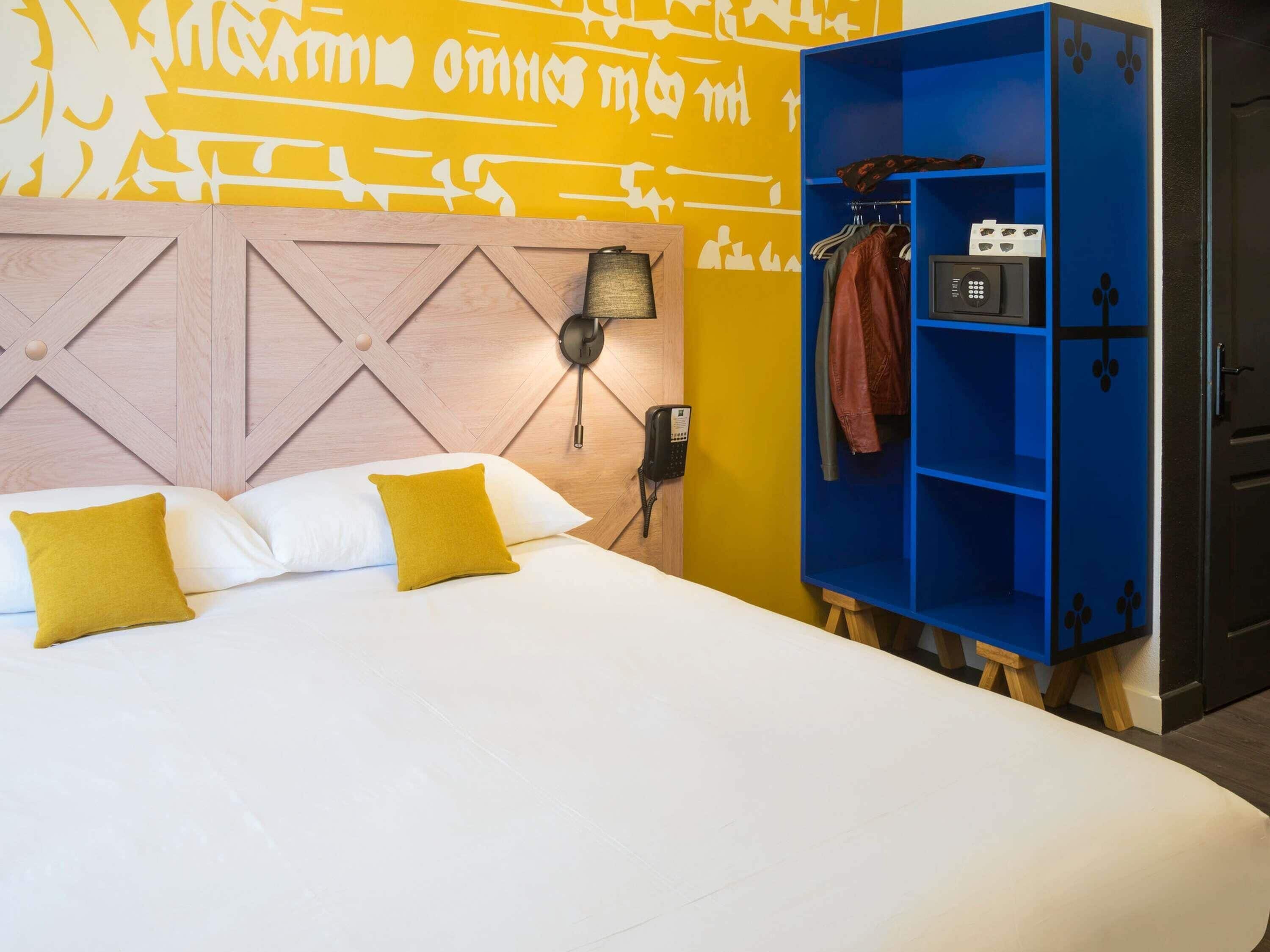 A hotel room with a bed, a phone, and a blue wardrobe.