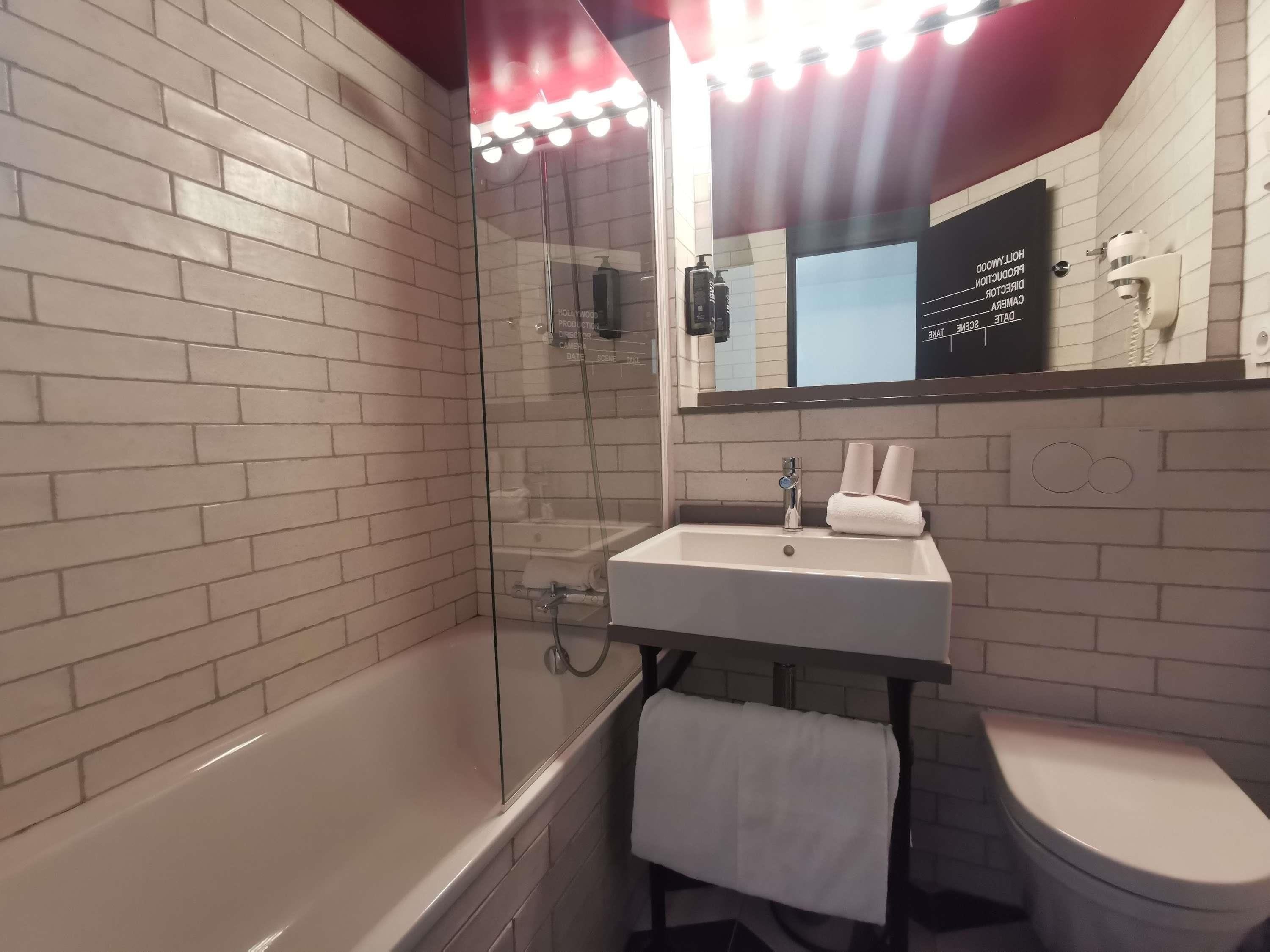 Een badkamer met een douchecabine van glas, een witte wastafel en een toilet.