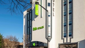 A modern hotel building with a prominent 'ibis style' sign, multiple windows, and a clear sky.