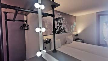 Una camera d'albergo con uno specchio trucco, luci, un letto e un affresco sulla parete.