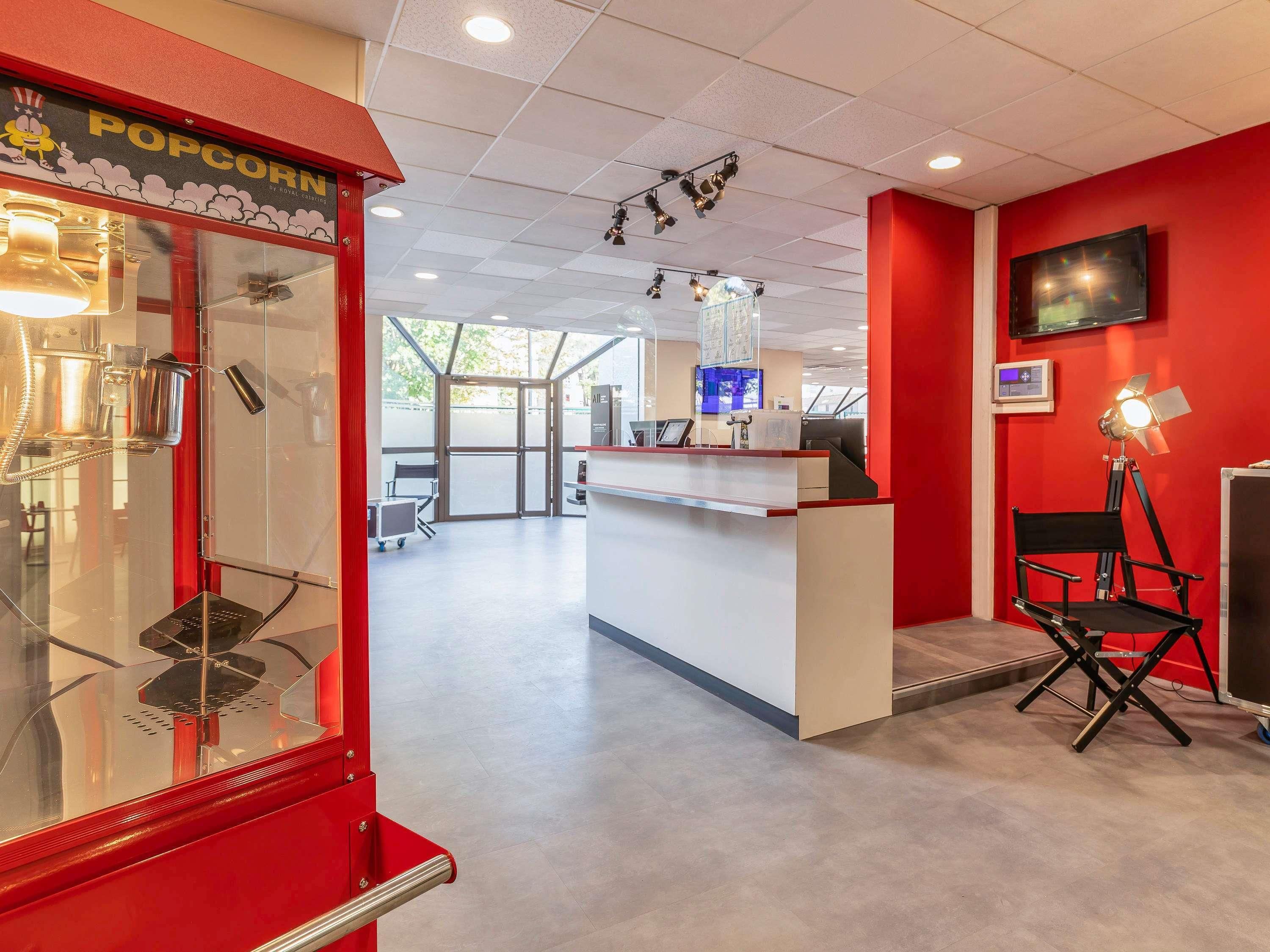A modern interior with a red wall, a popcorn machine, a desk, and a chair.