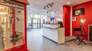 A modern interior with a red wall, a popcorn machine, a desk, and a chair.