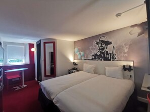 Une chambre d’hôtel équipée d’un lit, d’un bureau, d’une chaise et d’une grande fresque murale.