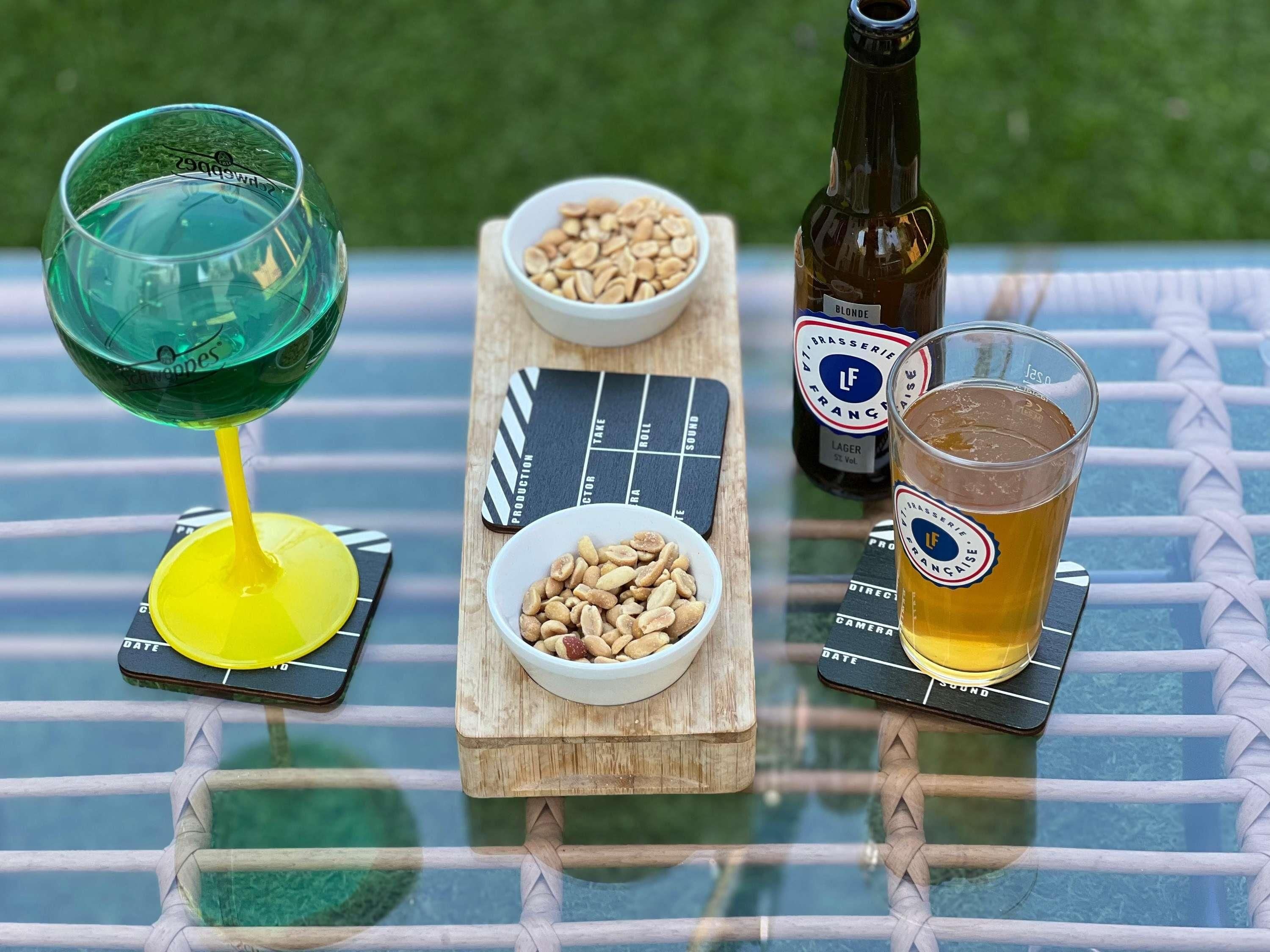 Een glazen tafel met een fles Blond Lager en twee schalen vol noten.
