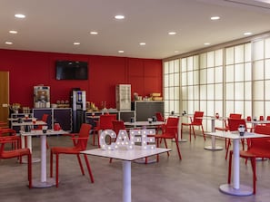 Een modern café met rode stoelen en tafels, een groot raam en een 'CAFE'-bord.