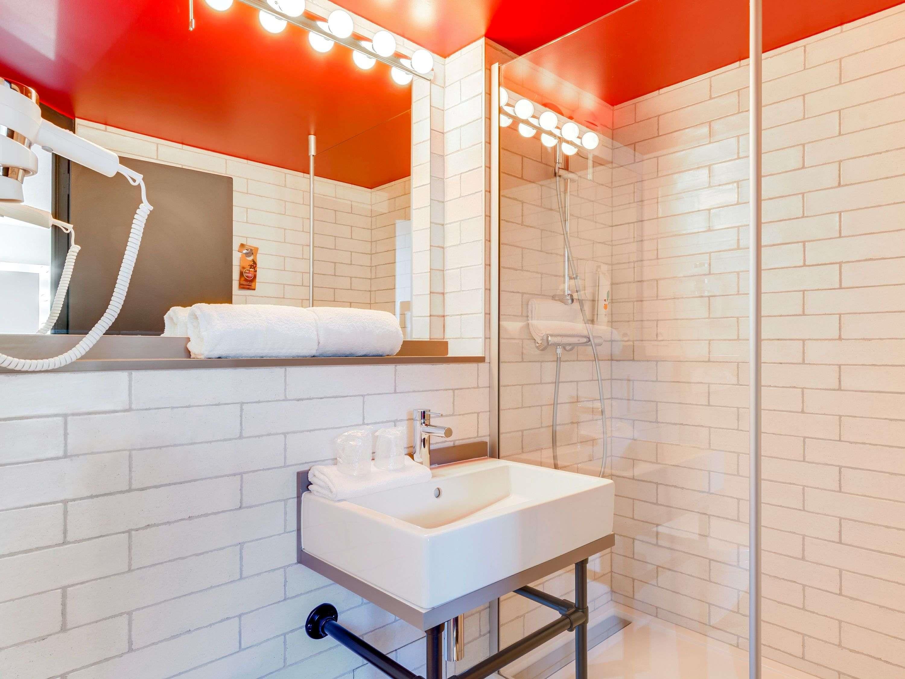 Een moderne badkamer met een wit wastafelmeubel, een spiegel en een douchecabine van glas.